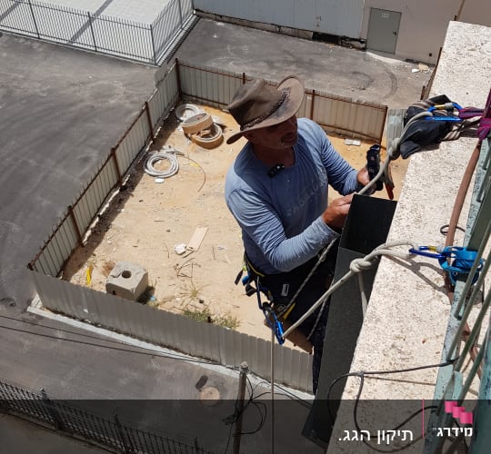 אדם עובד על גג עם חבלים וציוד בטיחות